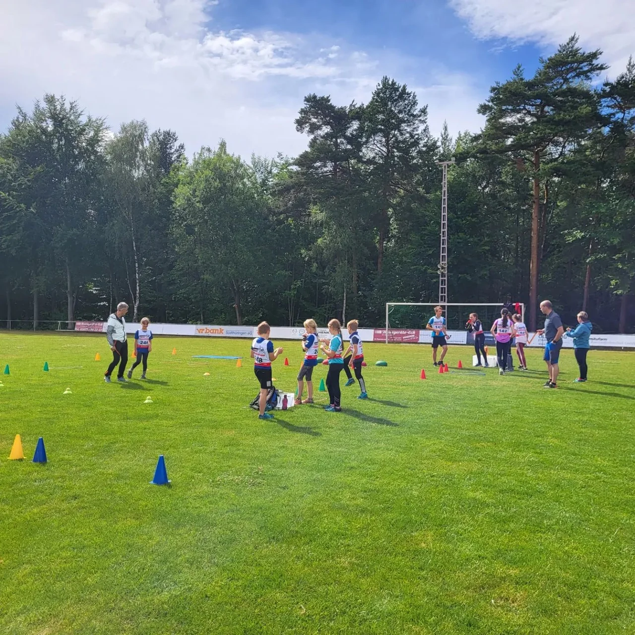 Kinder und Jugendliche beim gemeinsamen Sport auf einem Platz am Wald